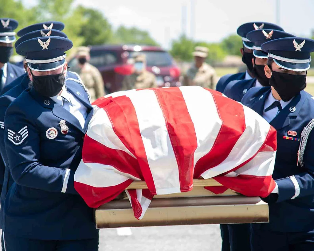 soldiers carrying a fallen soldier's coffin with flag atop
