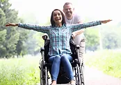 man in a sweater pushing a woman in checkered in a wheelchair