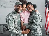 man and woman in uniform holding a child in pink shirt