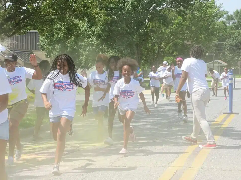 a group of people running on a road smiling and laughing